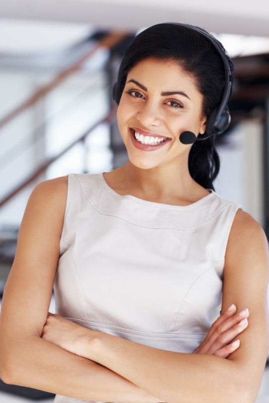 Portrait of happy female customer service executive with arms crossed.